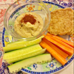 An image of a chickpea patty with humous, carrot and cucumber sticks.